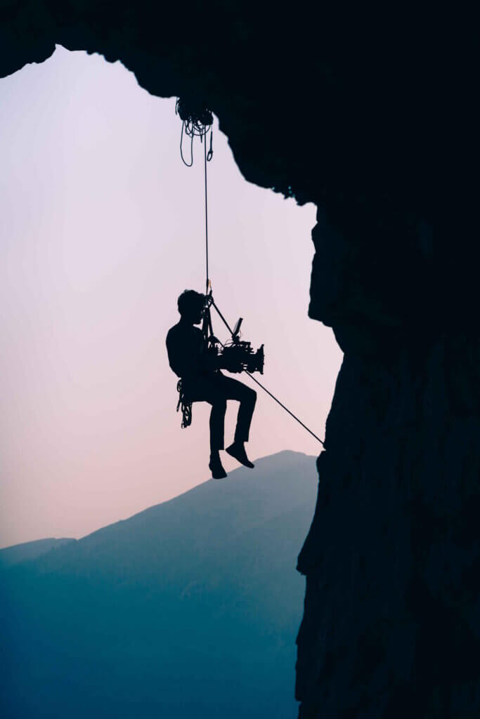 A Man Rappelling Down A Cliff