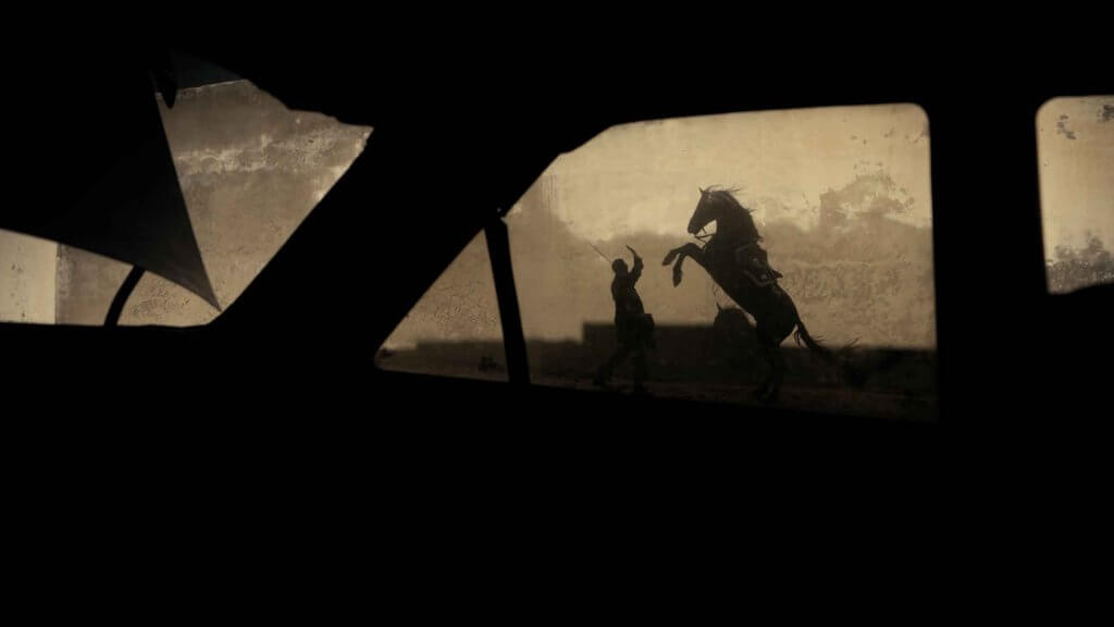 A horse can be seen jumping in front of a man