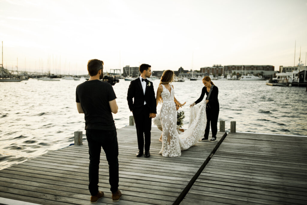Brendan & Chloe Simpson helping bride fix dress while on dock for photo