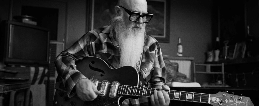 Older Man Playing The Guitar In His Home