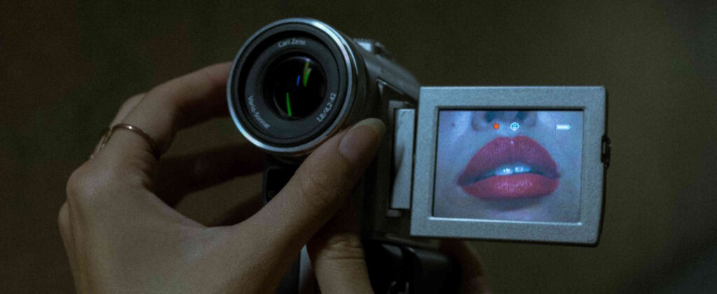 A woman with red lipstick holding a camcorder.