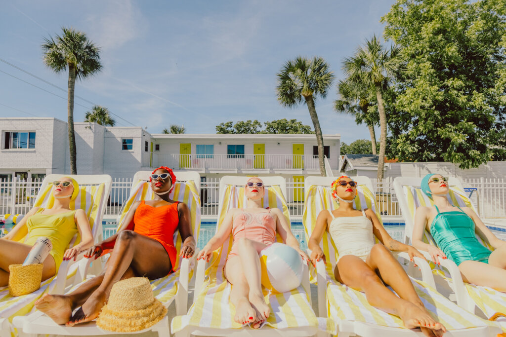 Five Women Are Laying Out On Pool Chairs Wearing Old Fashioned Bathing Suits