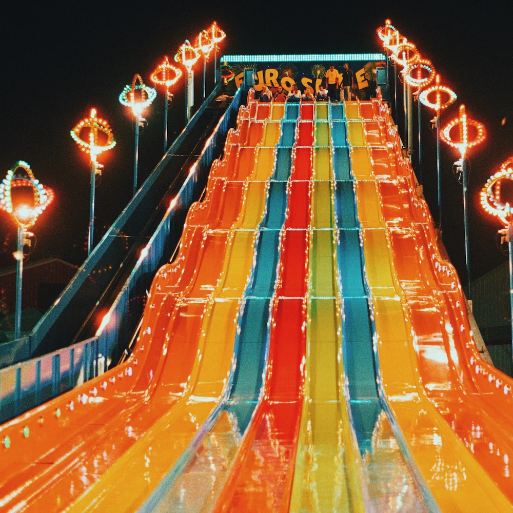 People Wait At The Top Of A Tall Slide In An Outdoor Location At Night Time