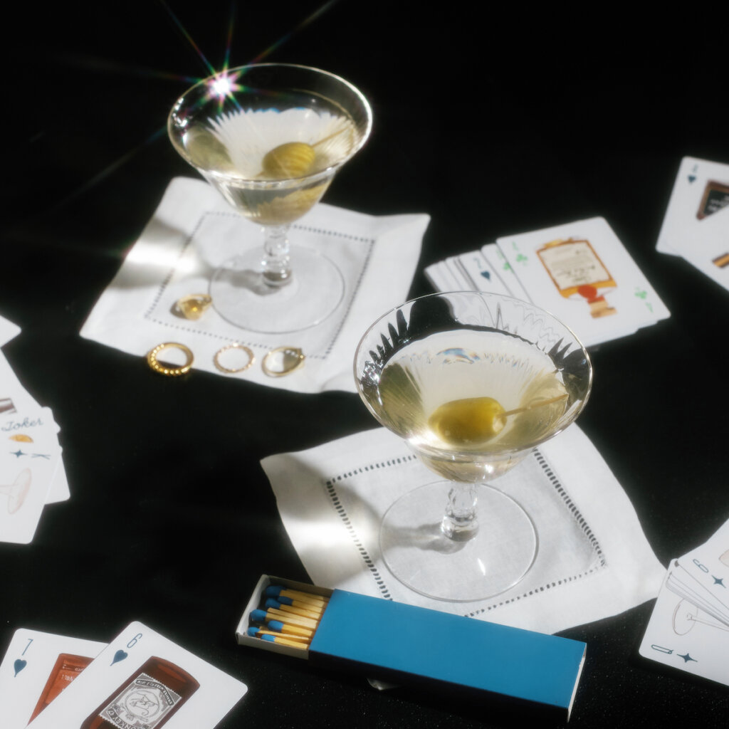 Two Prepared Martinis Sit On Top Of White Napkins On A Black Table Top