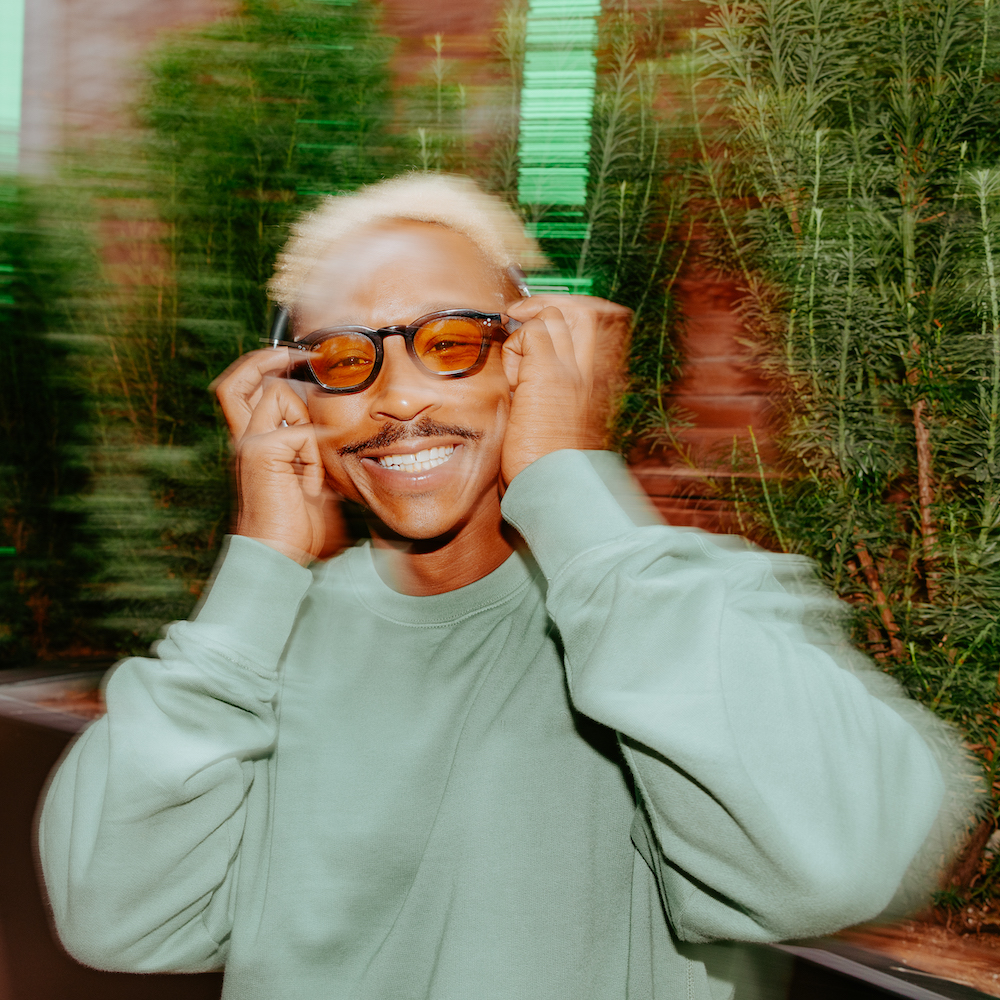 A Smiling Man In A Sweatshirt Listening To Headphones