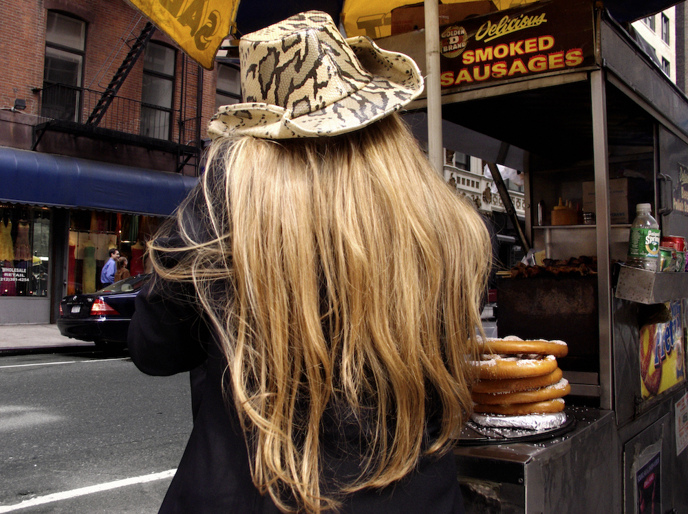 A Person Wearing A Cowboy Hat Eating Salt Pretzels Next To A Food Stand