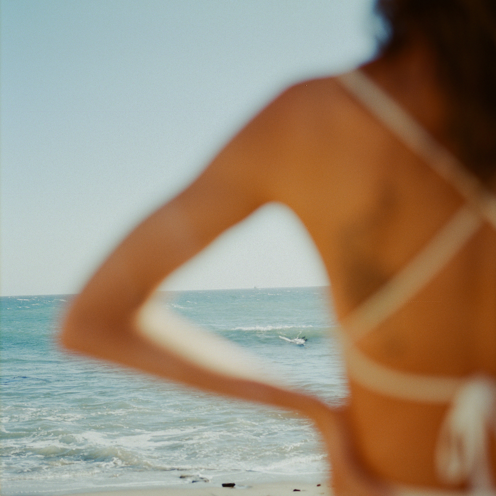 A Woman In A Bathing Suit Standing On A Beach