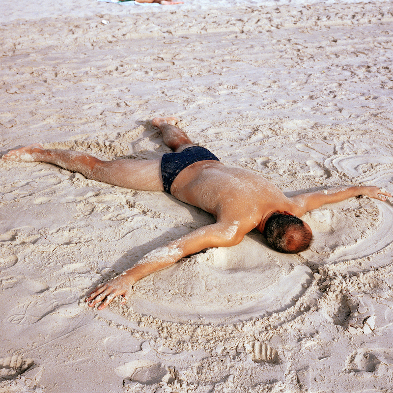 A Man Makes A Sand Angel On The Beach