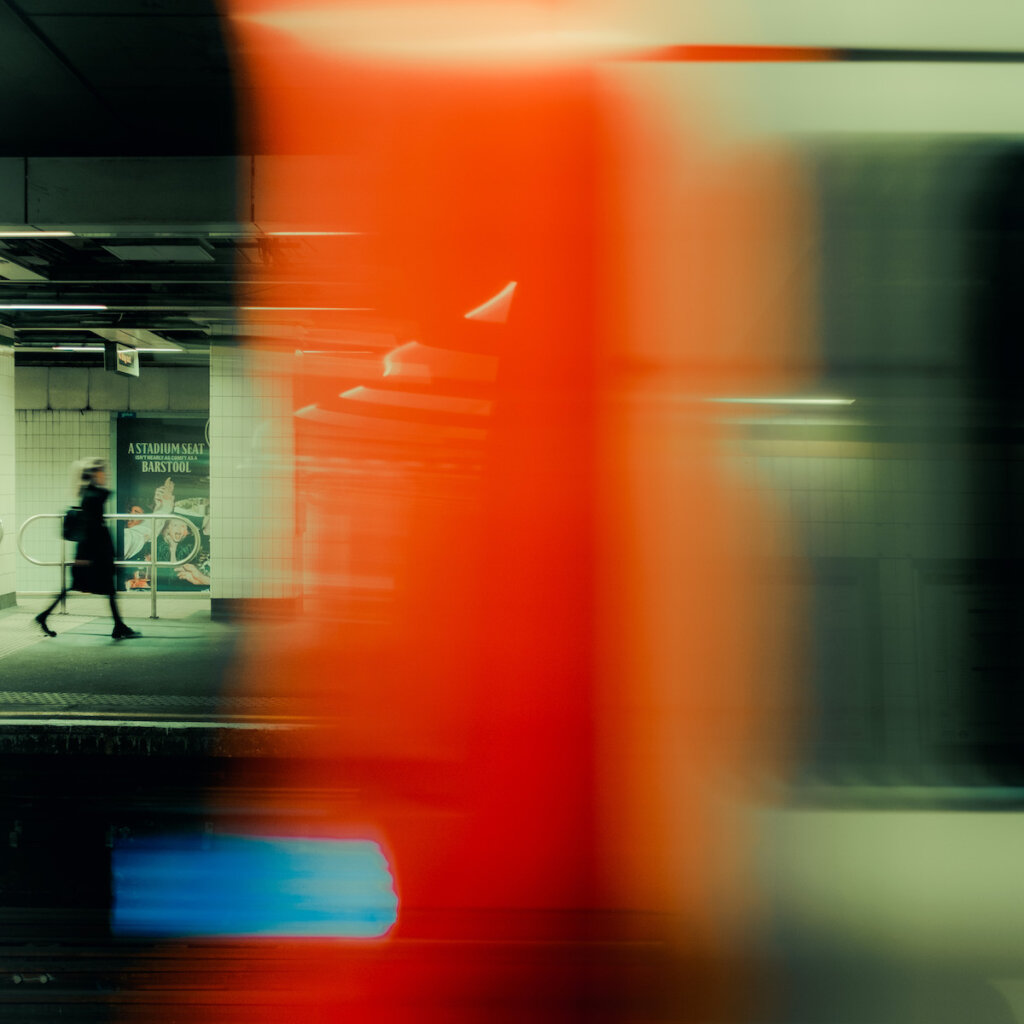 Train Passing By The Station While A Woman Walks On The Other Side